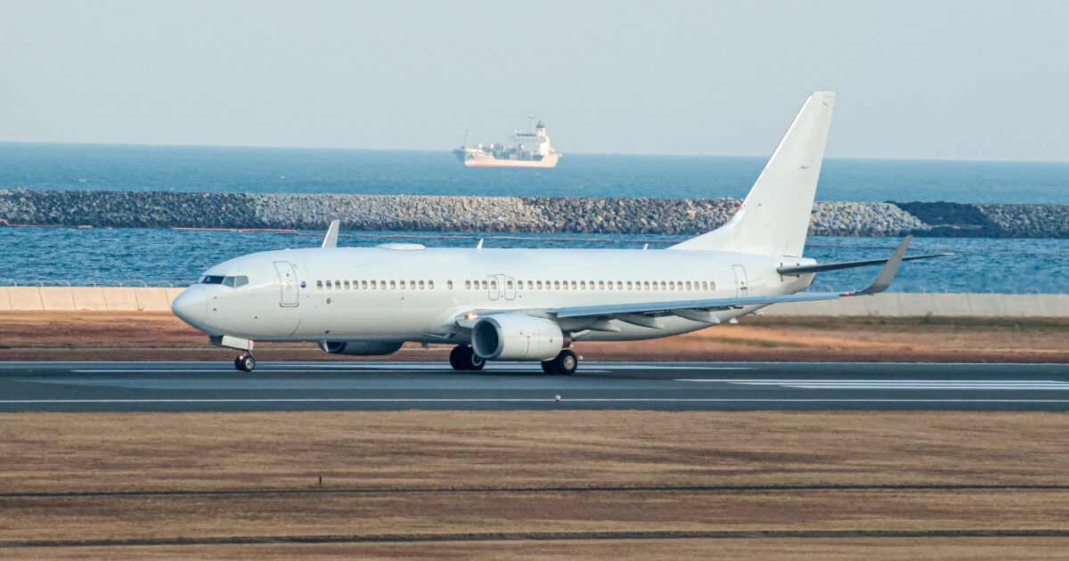 海沿いの滑走路を走行する白色のジェット旅客機