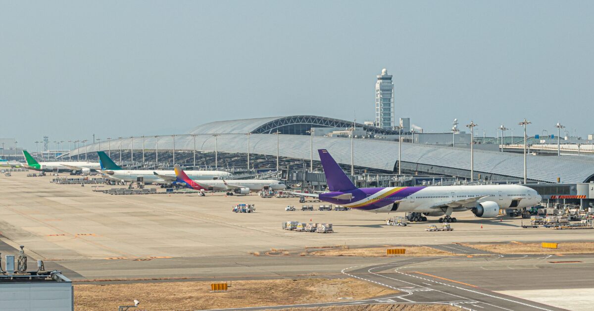 国際空港の駐機場に並ぶ複数の旅客機とターミナルビル