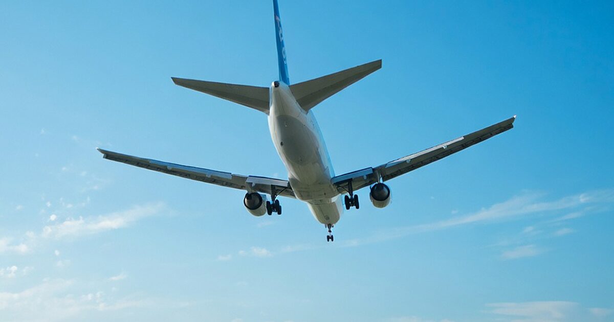 青空を背景に機体下部を捉えた着陸態勢の旅客機
