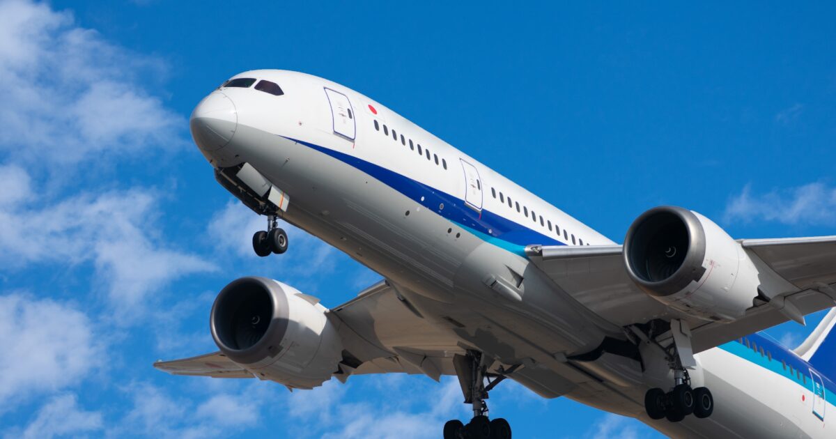 青空の下で低空飛行する着陸態勢のボーイング787旅客機