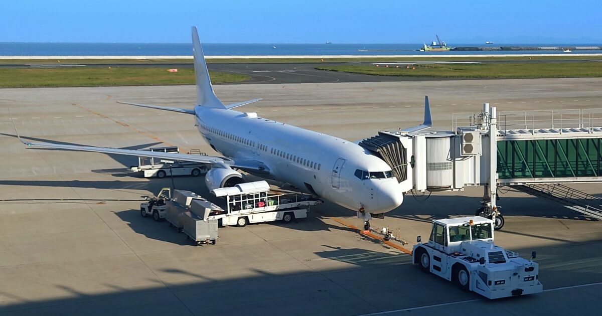 空港の搭乗ゲートに駐機するジェット旅客機と地上支援車両