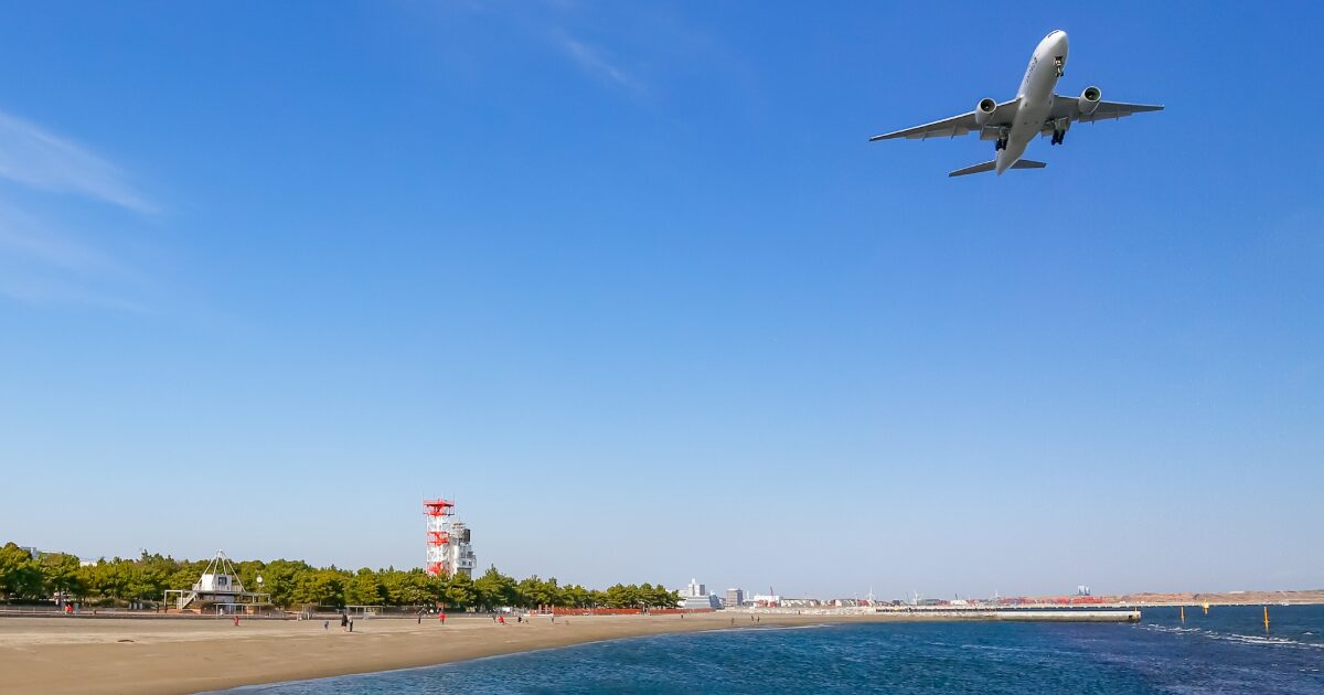 海岸上空を飛行する着陸態勢のジェット旅客機