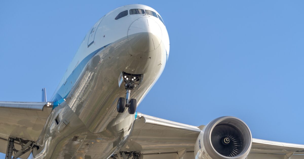 青空を背景に機体前方を捉えた着陸態勢の旅客機