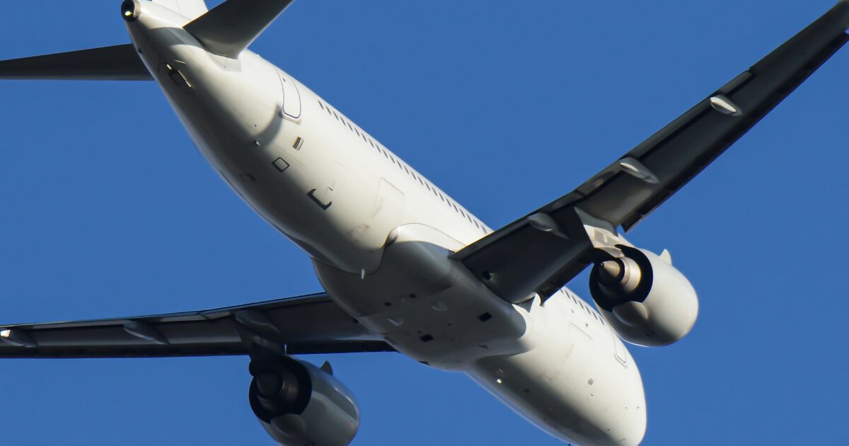 青空を低空飛行するジェット旅客機の機体下面