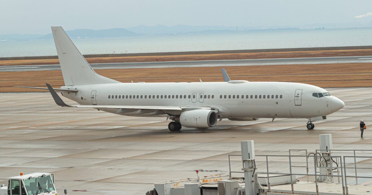 空港のエプロンを走行する白色の旅客機