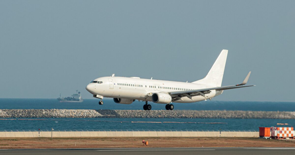 海沿いの滑走路に着陸する白色の旅客機