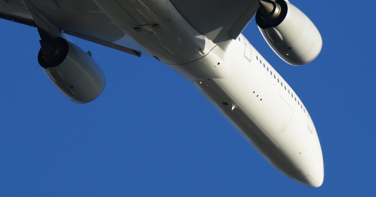 青空を背景に機体下部を捉えた双発ジェット旅客機