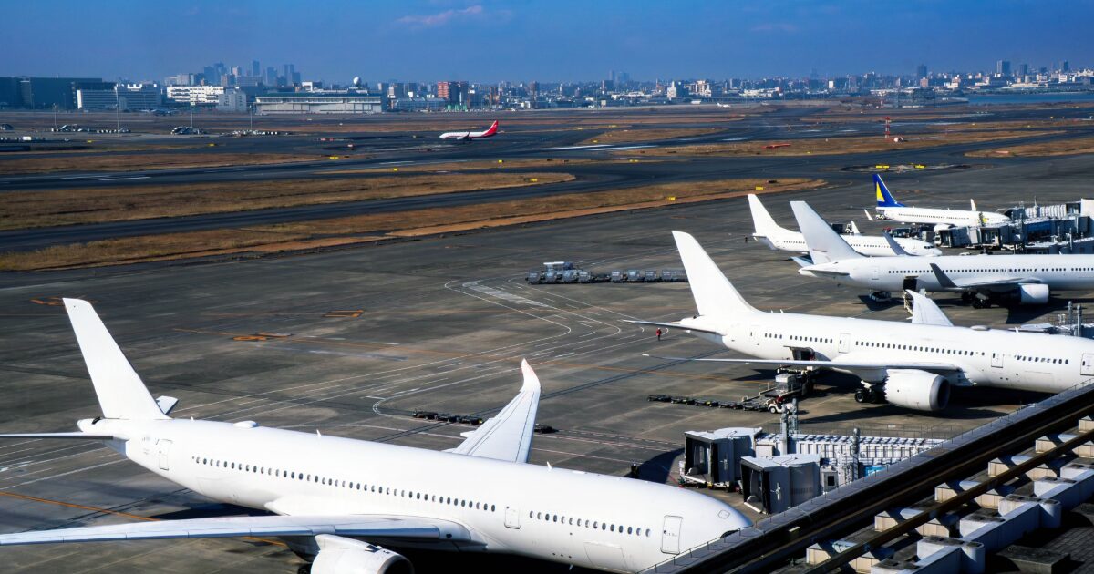 空港の駐機場に並ぶ複数の白色ジェット旅客機